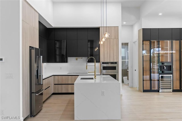 3620 SW 4th Ln, Cape Coral, FL 33991 - kitchen featuring modern cabinets, appliances with stainless steel finishes, wine cooler, light wood-style floors, and recessed lighting
