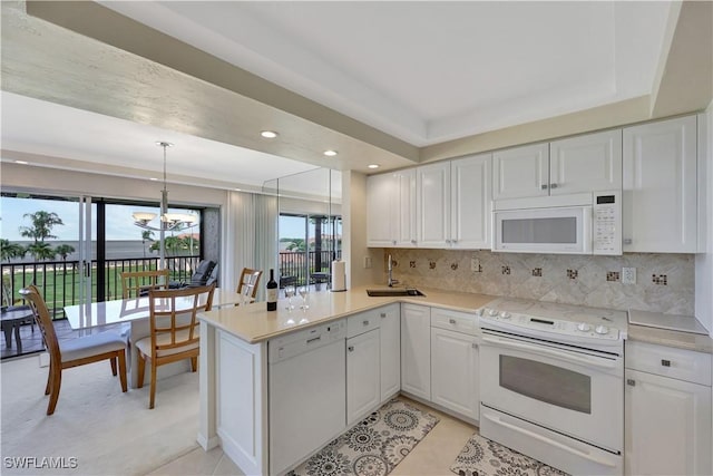 1080 S Collier Blvd Unit 305, Marco Island, FL 34145 - kitchen featuring white appliances, a peninsula, a chandelier, white cabinets, and light countertops