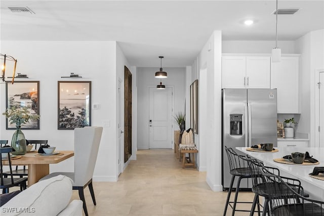 17752 Saddleback Loop, North Fort Myers, FL 33917 - kitchen featuring stainless steel fridge with ice dispenser, white cabinetry, light countertops, and a breakfast bar area