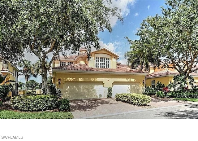 20250 Burnside Pl Unit 1502, Estero, FL 33928 - mediterranean / spanish house with driveway, stucco siding, a tiled roof, and a garage