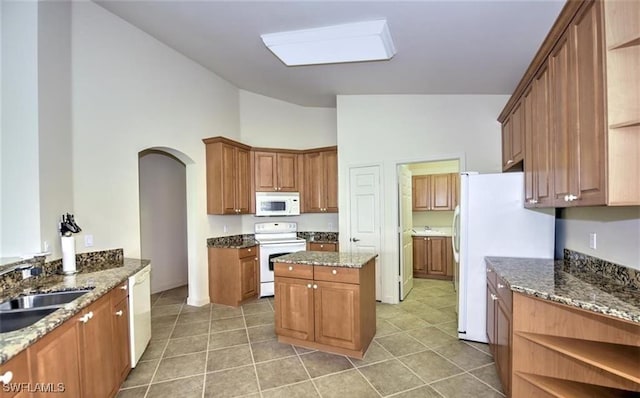20250 Burnside Pl Unit 1502, Estero, FL 33928 - kitchen with white appliances, arched walkways, stone counters, open shelves, and high vaulted ceiling