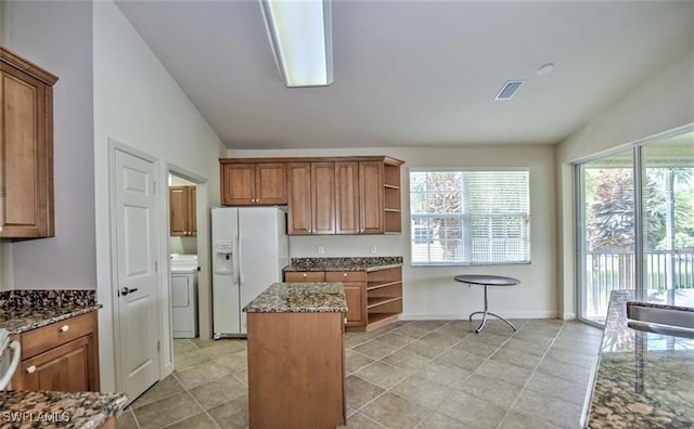 20250 Burnside Pl Unit 1502, Estero, FL 33928 - kitchen with white refrigerator with ice dispenser, vaulted ceiling, washer / dryer, open shelves, and dark stone counters