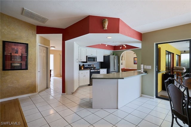 17139 Knight Dr, Fort Myers, FL 33967 - kitchen with appliances with stainless steel finishes, white cabinets, a peninsula, arched walkways, and light tile patterned floors