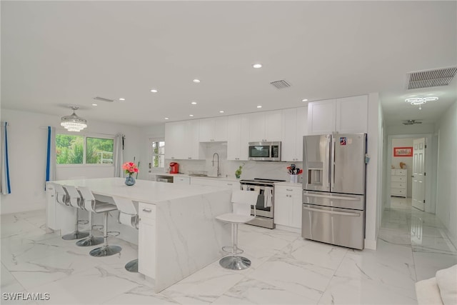 14539 Riverside Dr, Fort Myers, FL 33905 - kitchen with stainless steel appliances, white cabinetry, a kitchen breakfast bar, and recessed lighting