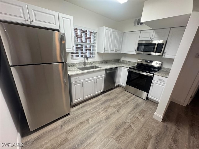 2590 1st St Unit 112, Fort Myers, FL 33901 - kitchen featuring stainless steel appliances, white cabinets, light wood finished floors, and light stone countertops