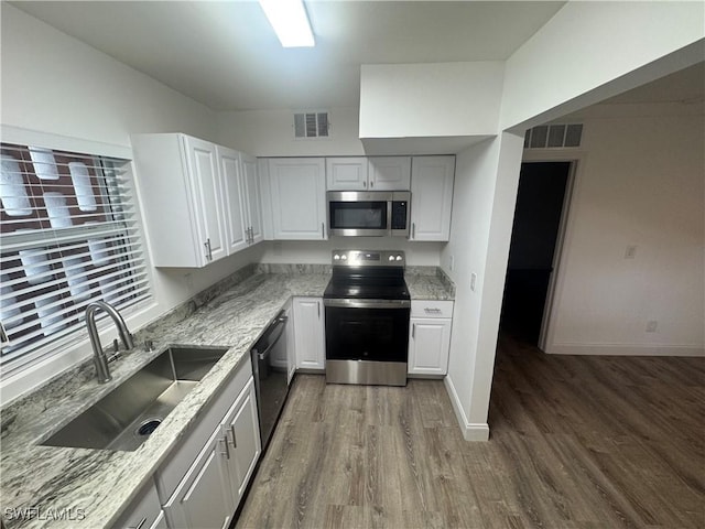 2590 1st St Unit 112, Fort Myers, FL 33901 - kitchen featuring stainless steel appliances, wood finished floors, light stone countertops, and white cabinets