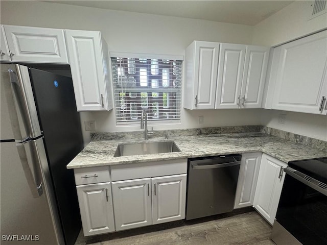 2590 1st St Unit 112, Fort Myers, FL 33901 - kitchen with stainless steel appliances, white cabinets, wood finished floors, and light stone countertops