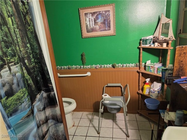 bathroom with a wainscoted wall and tile patterned flooring