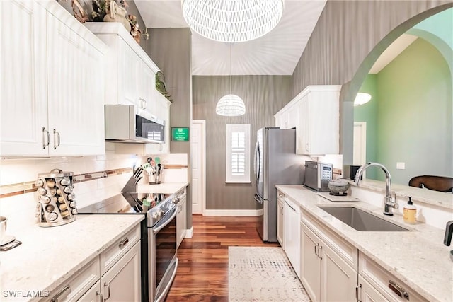15139 Ligustrum Ln, Alva, FL 33920 - kitchen featuring appliances with stainless steel finishes, arched walkways, white cabinetry, wood finished floors, and tasteful backsplash