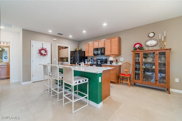 20095 Fiddlewood Ave, North Fort Myers, FL 33917 - kitchen with black appliances, an island with sink, a breakfast bar area, light countertops, and recessed lighting