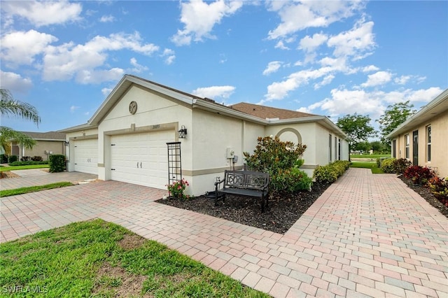 20095 Fiddlewood Ave, North Fort Myers, FL 33917 - view of side of property with stucco siding, decorative driveway, and an attached garage