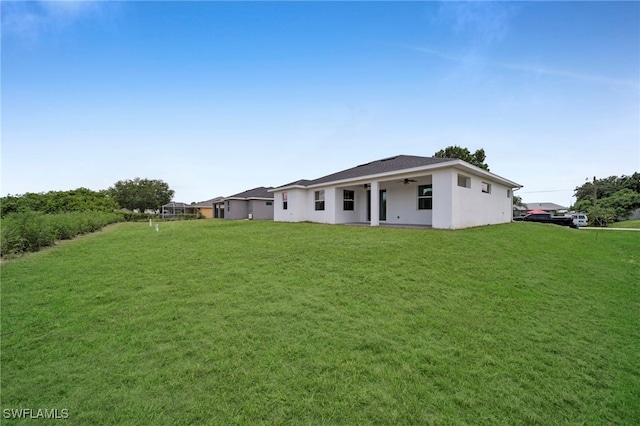 3706 16th St W, Lehigh Acres, FL 33971 - back of property featuring a ceiling fan, a yard, and stucco siding