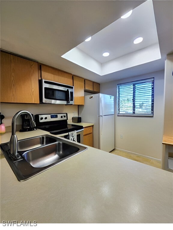 1221 Barrett Rd Unit 905, North Fort Myers, FL 33903 - kitchen featuring appliances with stainless steel finishes, brown cabinetry, a raised ceiling, light countertops, and recessed lighting