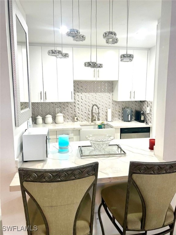 1395 NE 167th St # 107, North Miami Beach, FL 33162 - kitchen featuring white cabinets, backsplash, a kitchen bar, dishwasher, and decorative light fixtures