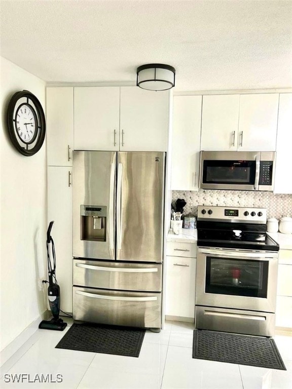 1395 NE 167th St # 107, North Miami Beach, FL 33162 - kitchen featuring stainless steel appliances, light countertops, white cabinets, backsplash, and a textured ceiling