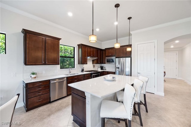 6787 Winding Cypress Dr, Naples, FL 34114 - kitchen with appliances with stainless steel finishes, arched walkways, backsplash, ornamental molding, and light countertops