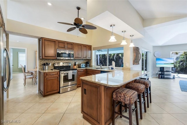 941 Ironwood Ct, Marco Island, FL 34145 - kitchen with stainless steel appliances, a peninsula, light tile patterned floors, a breakfast bar, and recessed lighting