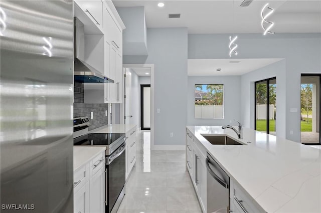 2218 SW 25th St, Cape Coral, FL 33914 - kitchen with appliances with stainless steel finishes, wall chimney exhaust hood, tasteful backsplash, white cabinetry, and recessed lighting