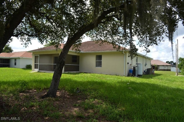3808 27th St SW, Lehigh Acres, FL 33976 - back of house with stucco siding, a yard, and a sunroom