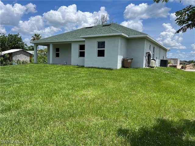 4208 28th St SW, Lehigh Acres, FL 33976 - rear view of house featuring stucco siding, roof with shingles, and a lawn