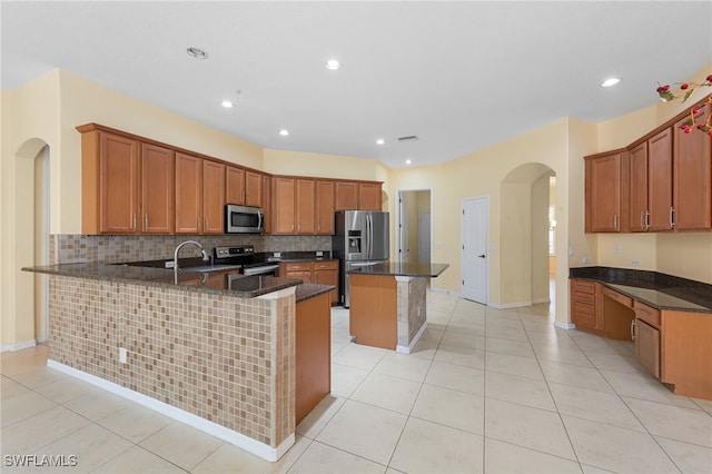 2628 Fairmont Cove Ct, Cape Coral, FL 33991 - kitchen with stainless steel appliances, arched walkways, a peninsula, backsplash, and dark stone countertops
