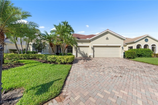 2628 Fairmont Cove Ct, Cape Coral, FL 33991 - view of front of home with an attached garage, decorative driveway, stucco siding, and a front lawn