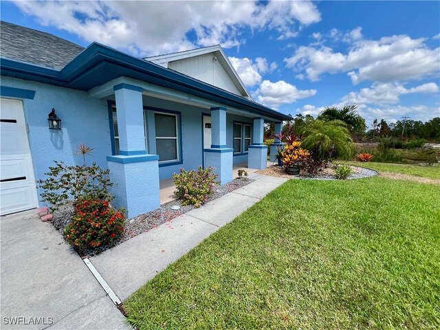 8000 Fountain Mist Blvd, Lehigh Acres, FL 33972 - view of home's exterior featuring a yard, a porch, and stucco siding