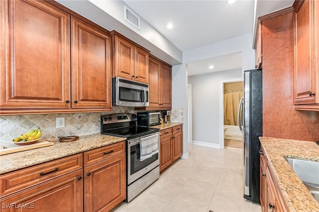 28082 Sosta Ln Unit 2, Bonita Springs, FL 34135 - kitchen featuring appliances with stainless steel finishes, brown cabinetry, backsplash, light stone counters, and recessed lighting