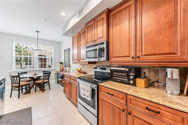 28082 Sosta Ln Unit 2, Bonita Springs, FL 34135 - kitchen featuring appliances with stainless steel finishes, brown cabinets, decorative backsplash, and light stone countertops
