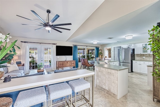 4512 SW 20th Ave, Cape Coral, FL 33914 - kitchen with freestanding refrigerator, french doors, white cabinets, a breakfast bar area, and lofted ceiling
