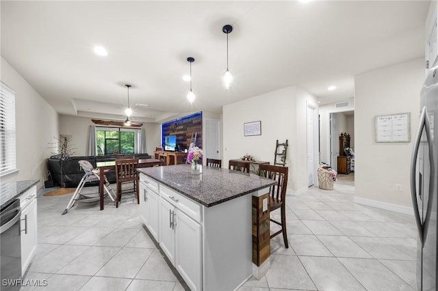 3336 Hampton Blvd, Alva, FL 33920 - kitchen with stainless steel appliances, light tile patterned floors, dark stone countertops, a kitchen bar, and white cabinetry