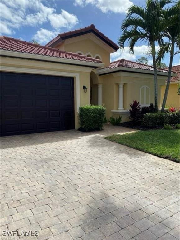11491 Axis Deer Ln, Fort Myers, FL 33966 - mediterranean / spanish-style home featuring decorative driveway, stucco siding, a tile roof, and an attached garage