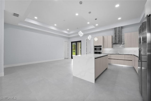 4234 27th Ave NE, Naples, FL 34120 - kitchen with modern cabinets, light brown cabinetry, a tray ceiling, appliances with stainless steel finishes, and wall chimney range hood