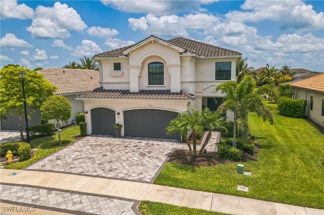 4692 Kensington Cir, Naples, FL 34119 - mediterranean / spanish house with stucco siding, a tiled roof, an attached garage, a front yard, and decorative driveway