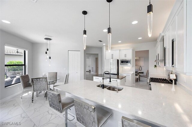 4692 Kensington Cir, Naples, FL 34119 - kitchen with stainless steel appliances, a peninsula, white cabinetry, light marble finish flooring, and light stone countertops