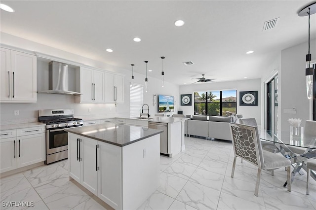 4692 Kensington Cir, Naples, FL 34119 - kitchen featuring stainless steel appliances, wall chimney range hood, a peninsula, a kitchen island, and recessed lighting