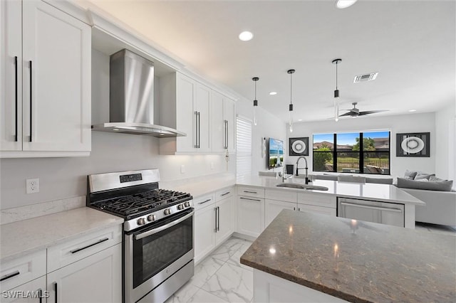 4692 Kensington Cir, Naples, FL 34119 - kitchen featuring wall chimney exhaust hood, appliances with stainless steel finishes, light marble finish floors, a ceiling fan, and a peninsula
