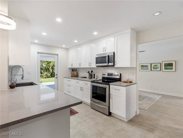 3704 Blue Heron Dr, Fort Myers, FL 33908 - kitchen featuring stainless steel appliances, backsplash, white cabinetry, light wood-type flooring, and recessed lighting