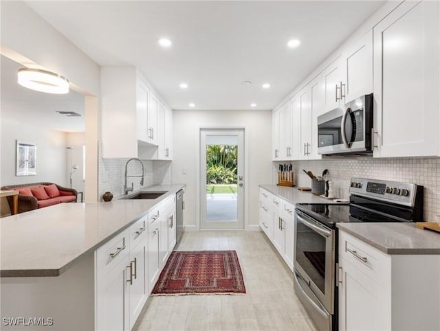 3704 Blue Heron Dr, Fort Myers, FL 33908 - kitchen featuring stainless steel appliances, tasteful backsplash, a peninsula, white cabinetry, and recessed lighting