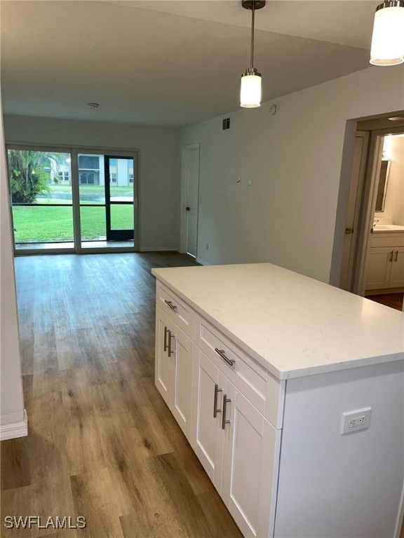 16881 Davis Rd Unit 713, Fort Myers, FL 33908 - kitchen with wood finished floors, white cabinets, a center island, decorative light fixtures, and open floor plan