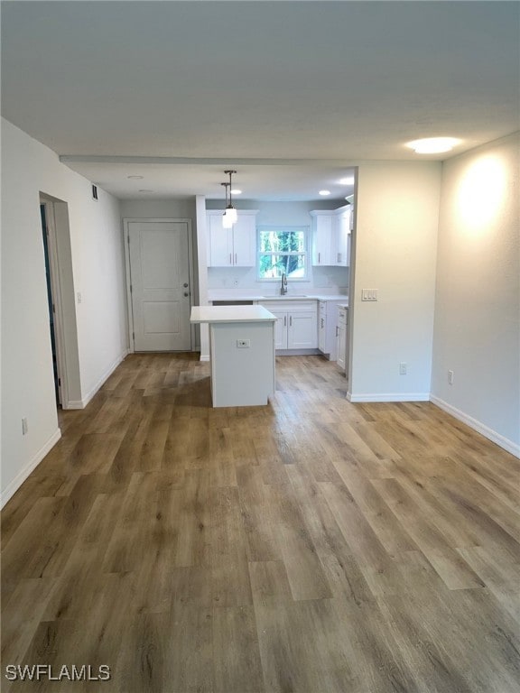 16881 Davis Rd Unit 713, Fort Myers, FL 33908 - kitchen featuring a center island, white cabinets, light wood-type flooring, light countertops, and hanging light fixtures