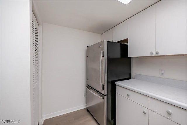 8441 N Haven Ln Unit B, Fort Myers, FL 33919 - kitchen with freestanding refrigerator, light countertops, white cabinetry, and light wood-style flooring