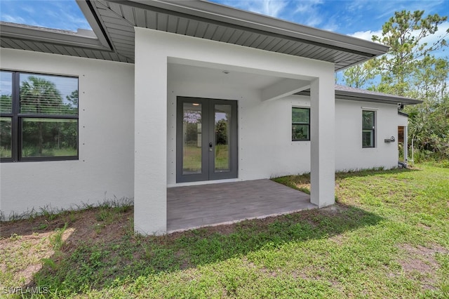 4447 26th Ave SE, Naples, FL 34117 - view of exterior entry featuring stucco siding, french doors, and a lawn