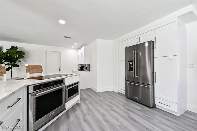 646 Park Shore Dr, Naples, FL 34103 - kitchen with stainless steel appliances, white cabinetry, light wood-style floors, light stone counters, and recessed lighting