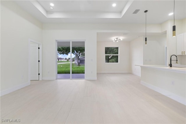3801 14th St W, Lehigh Acres, FL 33971 - unfurnished living room featuring healthy amount of natural light, a raised ceiling, light wood finished floors, and recessed lighting