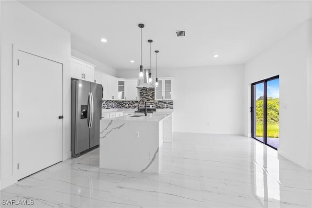 7071 Tide Cir, Labelle, FL 33935 - kitchen featuring stainless steel fridge with ice dispenser, wall chimney range hood, light marble finish floors, a center island with sink, and glass insert cabinets