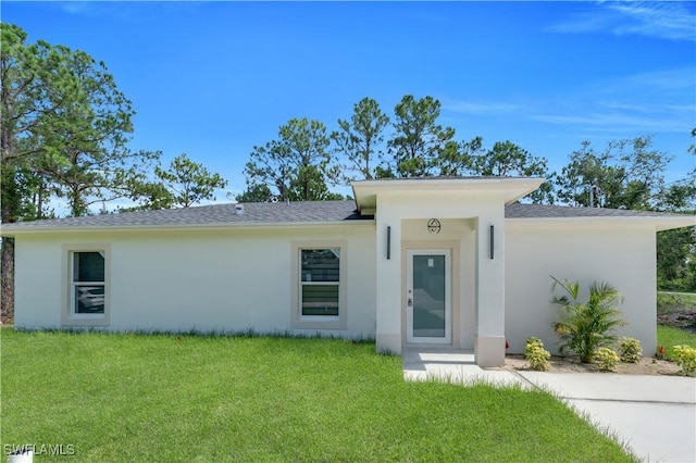 1132 Ravenswood St E, Lehigh Acres, FL 33974 - view of front of property featuring stucco siding, a front lawn, and a shingled roof