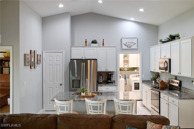 2804 NW 6th St, Cape Coral, FL 33993 - kitchen featuring stainless steel appliances, a breakfast bar area, white cabinets, dark stone counters, and washing machine and dryer