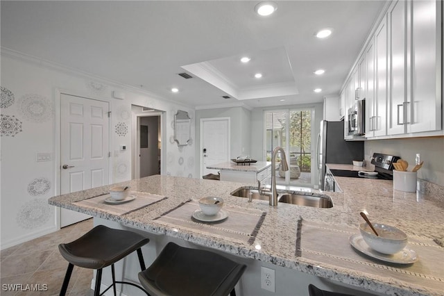 14040 Heritage Landing Blvd Unit 115, Punta Gorda, FL 33955 - kitchen featuring stainless steel appliances, light stone counters, a breakfast bar, ornamental molding, and white cabinets