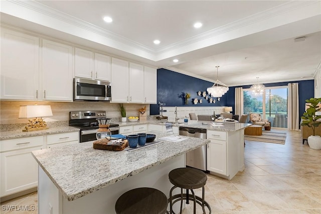 14040 Heritage Landing Blvd Unit 124, Punta Gorda, FL 33955 - kitchen featuring appliances with stainless steel finishes, a peninsula, a center island, ornamental molding, and white cabinets